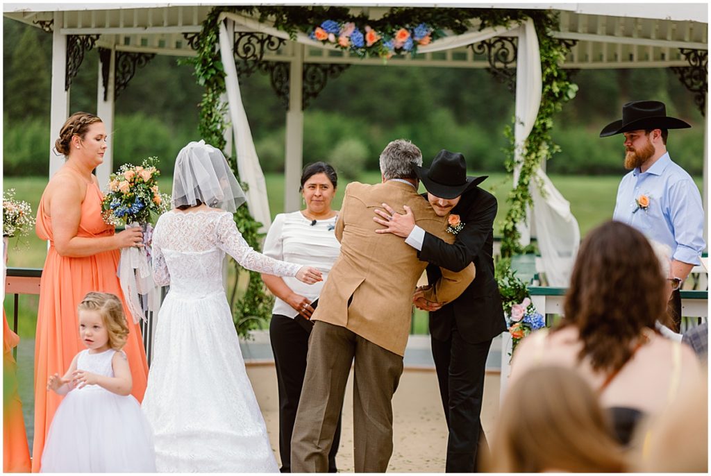 Father of bride and groom hug before ceremony at Deer Creek Valley Ranch