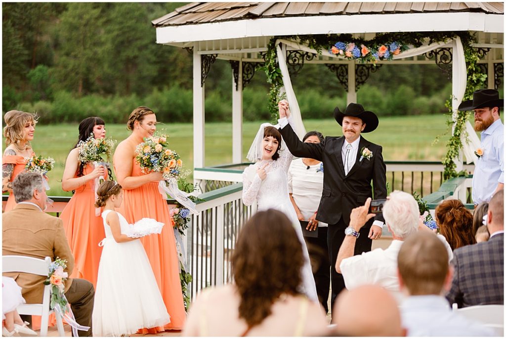Bride and groom holding and raising hands up after ceremony at Deer Creek Valley Ranch