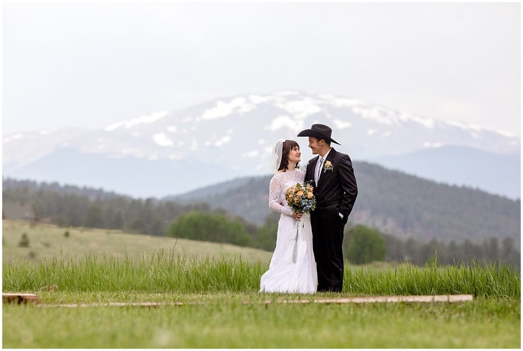 Bride and groom with snow capped mountains in background at Deer Creek Valley Ranch