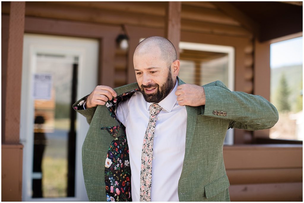 Groom putting on Indochino suit at Piney River Ranch in Vail