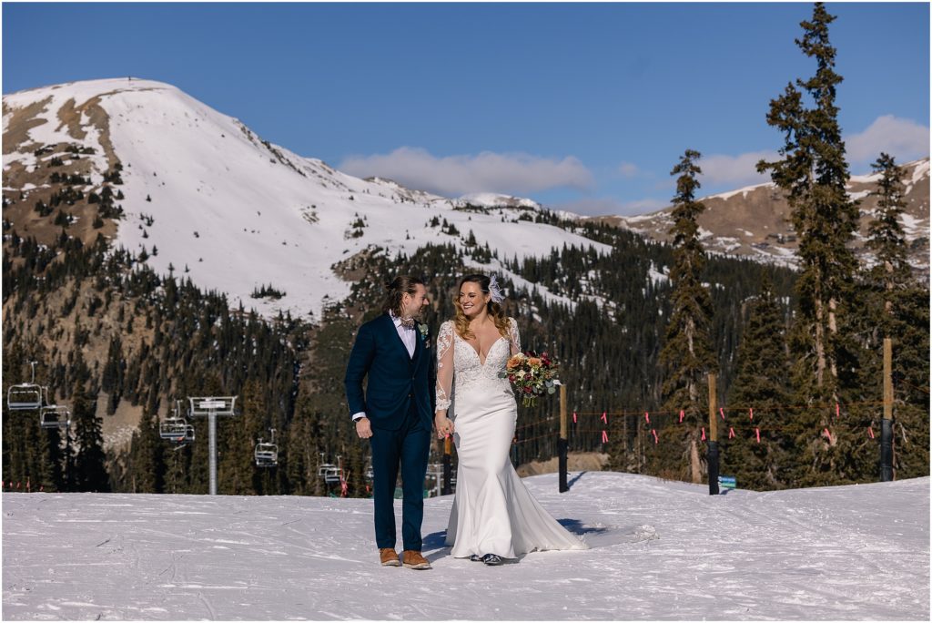 Bride and groom walking down mountain at Arapahoe Basin