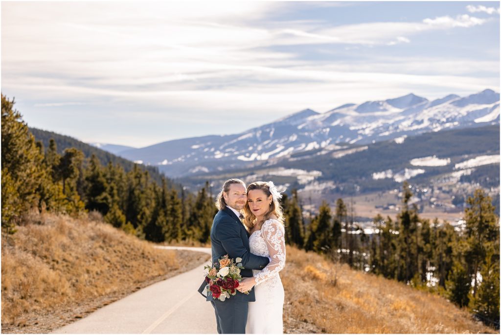 Bride and groom kissing on road near Arapahoe Basin.  Bride holding bouquet by Plum Sage Flowers