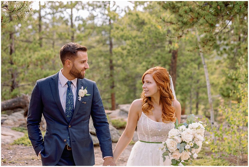 Bride wearing dress from BHLDN and designed by Watters for fall elopement at Blue Sky Mountain Ranch in Blackhawk walking with groom wearing suit from Indochino.  Bride holding bouquet designed by Blush & Bay.