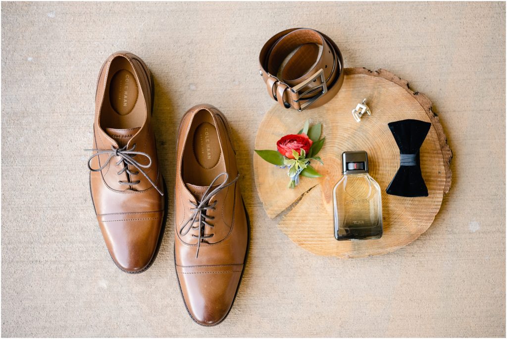 Flat layout of grooms cologne, boutonniere, belt, bowtie and shoes before wedding