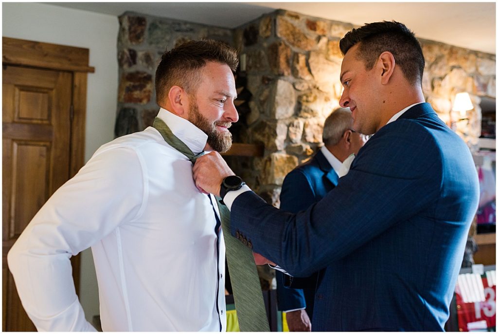 Groom putting on suit at Donovan Pavilion in Vail for wedding.