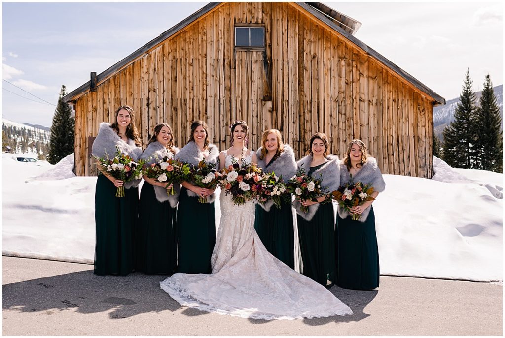 Bridesmaids outside at Keystone Ranch holding bouquets designed by Bloom Flower Shop.  Bridesmaids wearing dress from Birdy Grey.