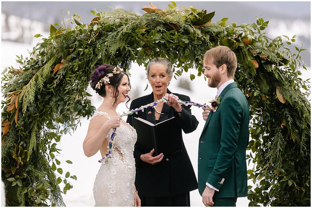 Bride and groomBride and groom holding flower rope during ceremony