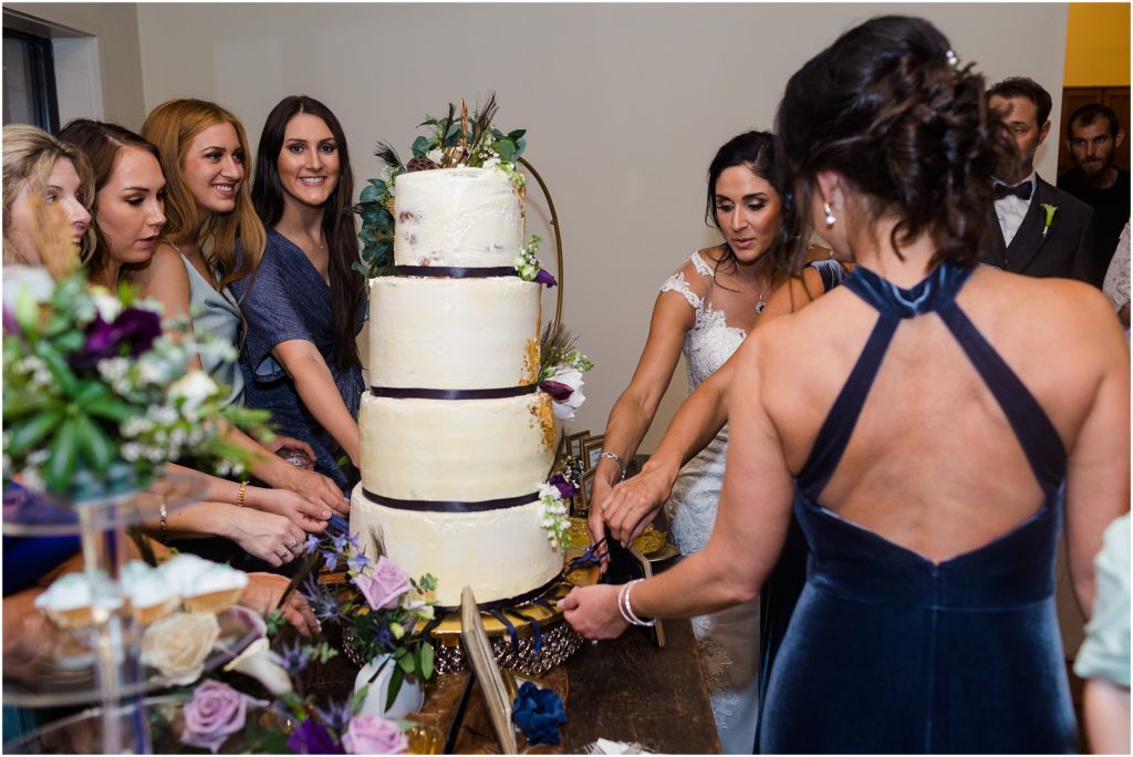 Bridal party gathered around wedding cake designed by Bright Dawn Kitchen.