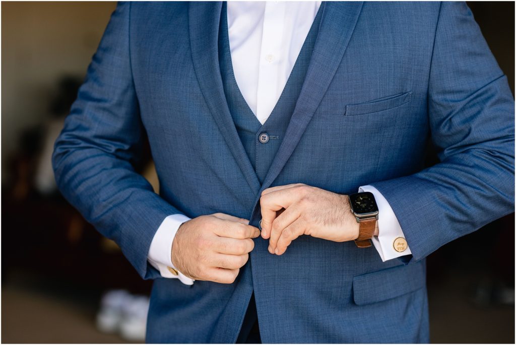 Groom buttoning suit and getting ready for wedding.