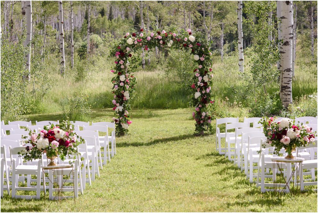 Wedding arch and aisle outside at Flying Diamond Ranch in Steamboat Springs with floral design by We Plus You.