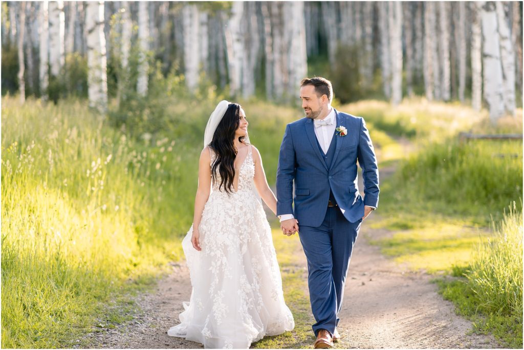 Bride and groom walking on trail with aspen trees after wedding ceremony at Flying Diamond Ranch in Steamboat Springs