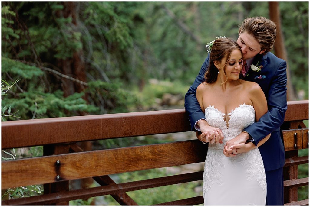 Bride and groom on bridge at Vail mountain.  Bride holding bouquet designed by Fancy Pansy.