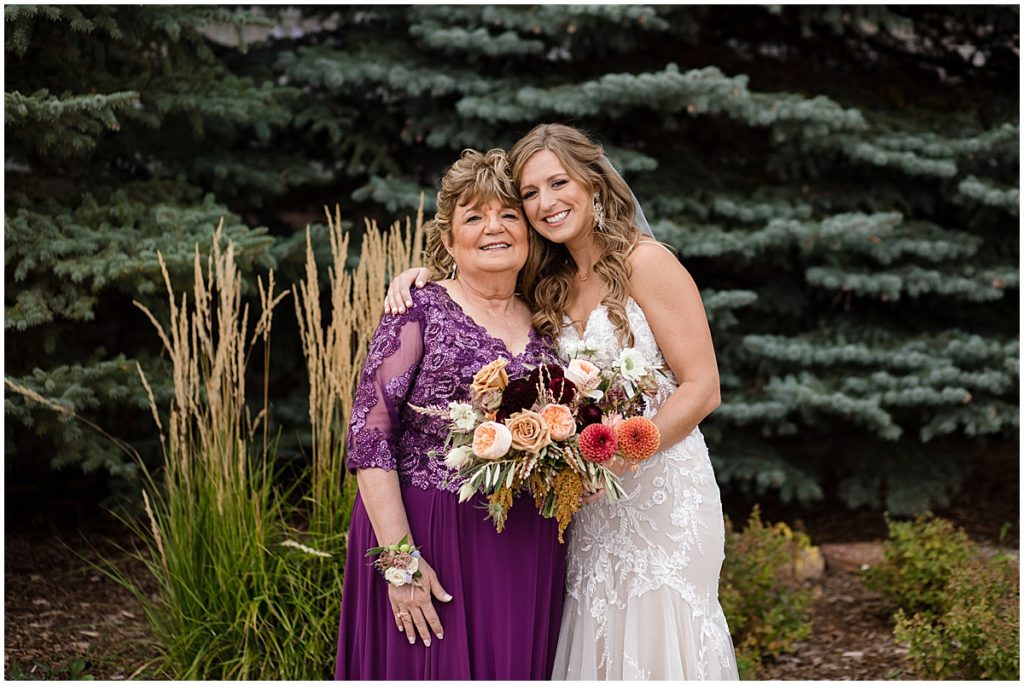 Bride wearing wedding dress from Town and Country Bridal with her mom holding bouquet by Lace and Lilies Flowers.