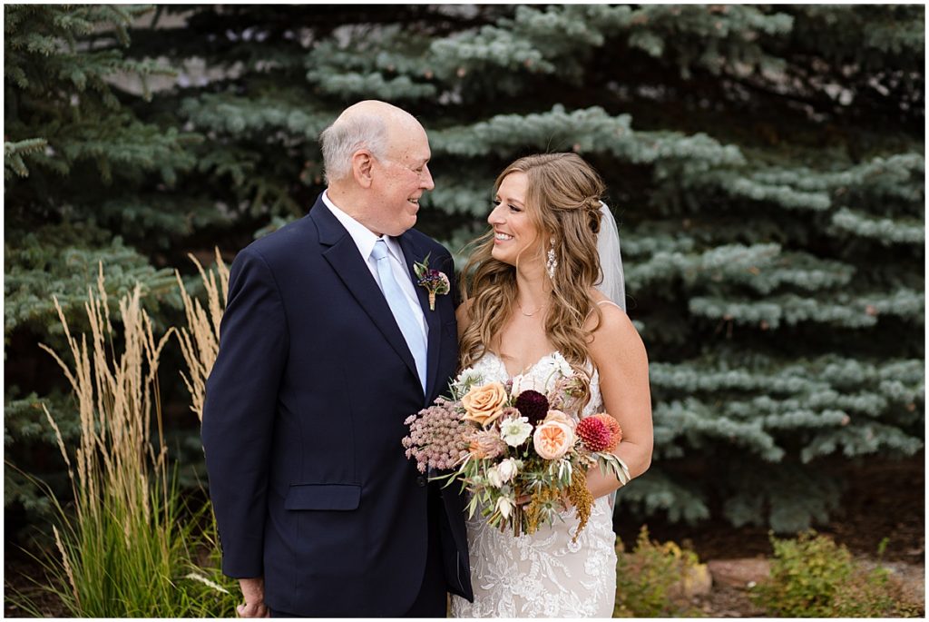 Bride wearing wedding dress from Town and Country Bridal with her dad holding bouquet by Lace and Lilies Flowers.