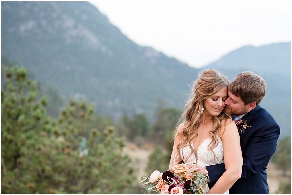 Bride and groom outside at the Stanley Hotel in Estes Park.  Bride is wearing dress from Town and Country Bridal holding bouquet from Lace and Lilies Flowers.  Groom wearing suit from Jos A Bank.