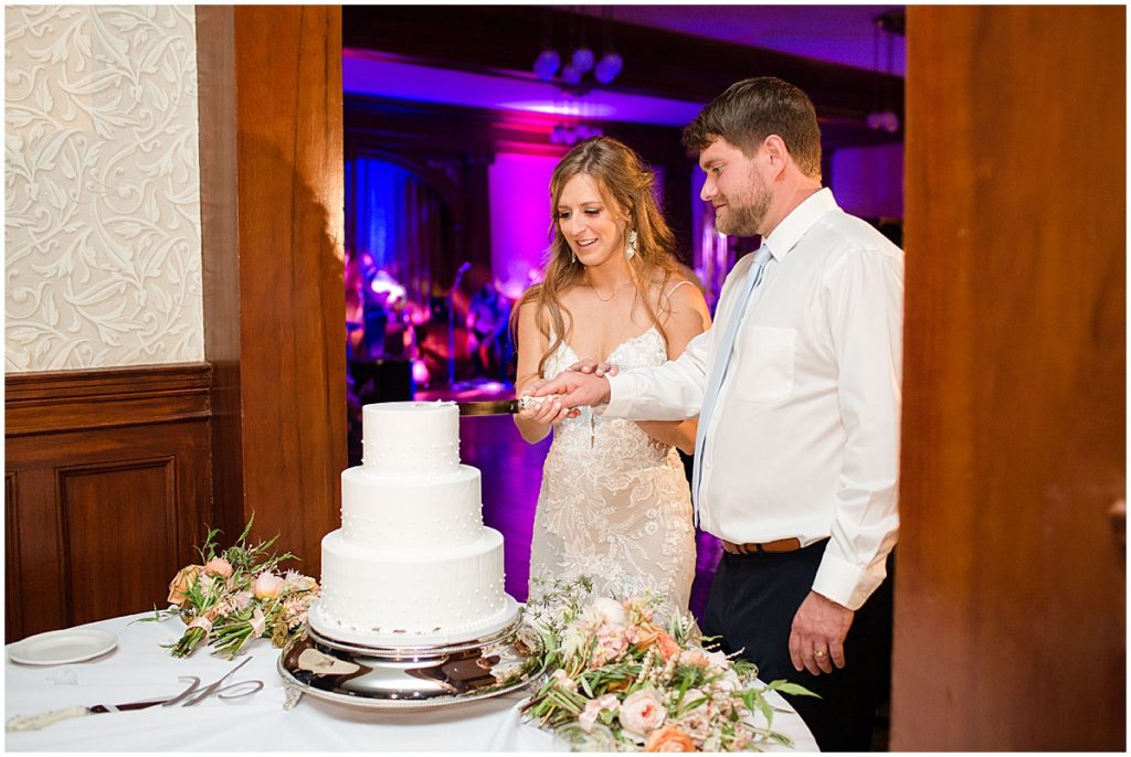 Wedding cake by Colorado Rose Cake Company being cut by bride and groom at the Stanley Hotel in Estes Park.