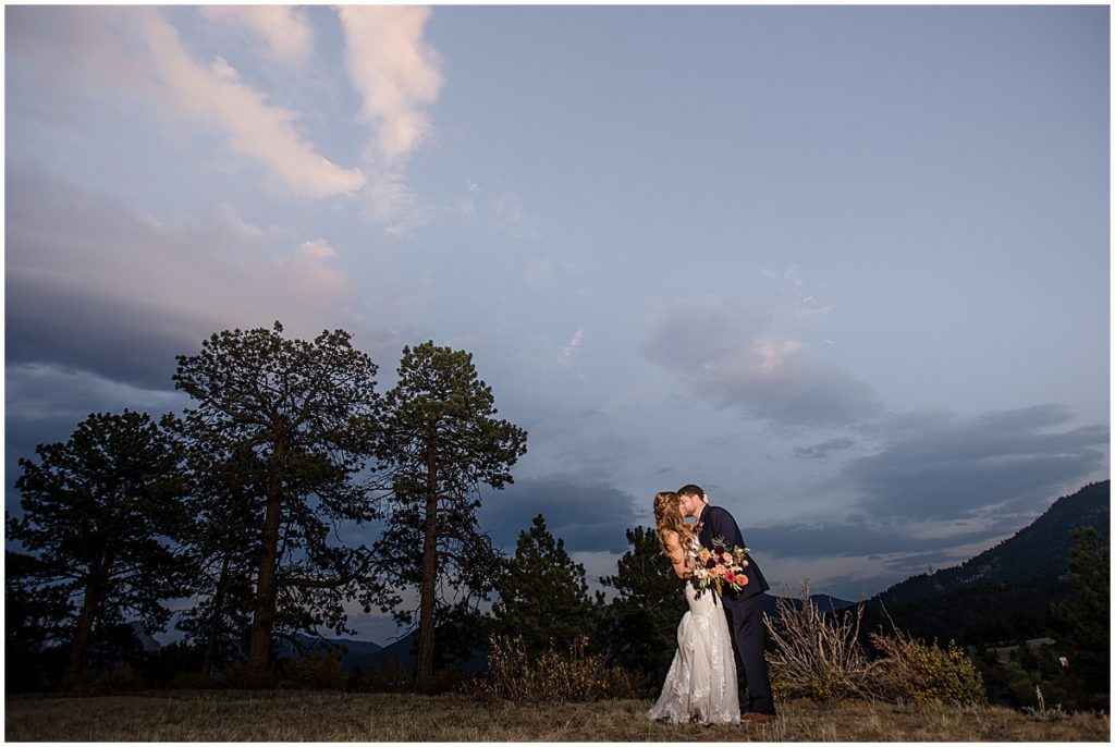 Bride and groom outside at the Stanley Hotel in Estes Park.  Bride is wearing dress from Town and Country Bridal holding bouquet from Lace and Lilies Flowers.  Groom wearing suit from Jos A Bank.