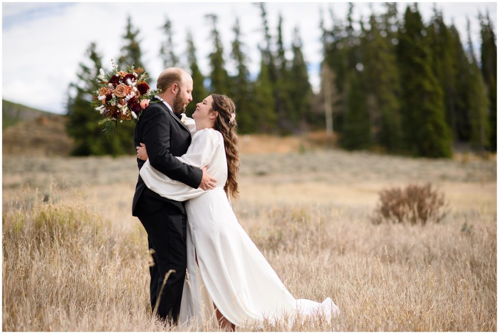 Bride and groom outside in the Colorado fall mountains.  Bride holding bouquet from Petal and Bean