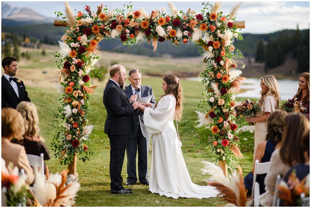 Bride and groom under arch at wedding ceremony at Keystone Ranch