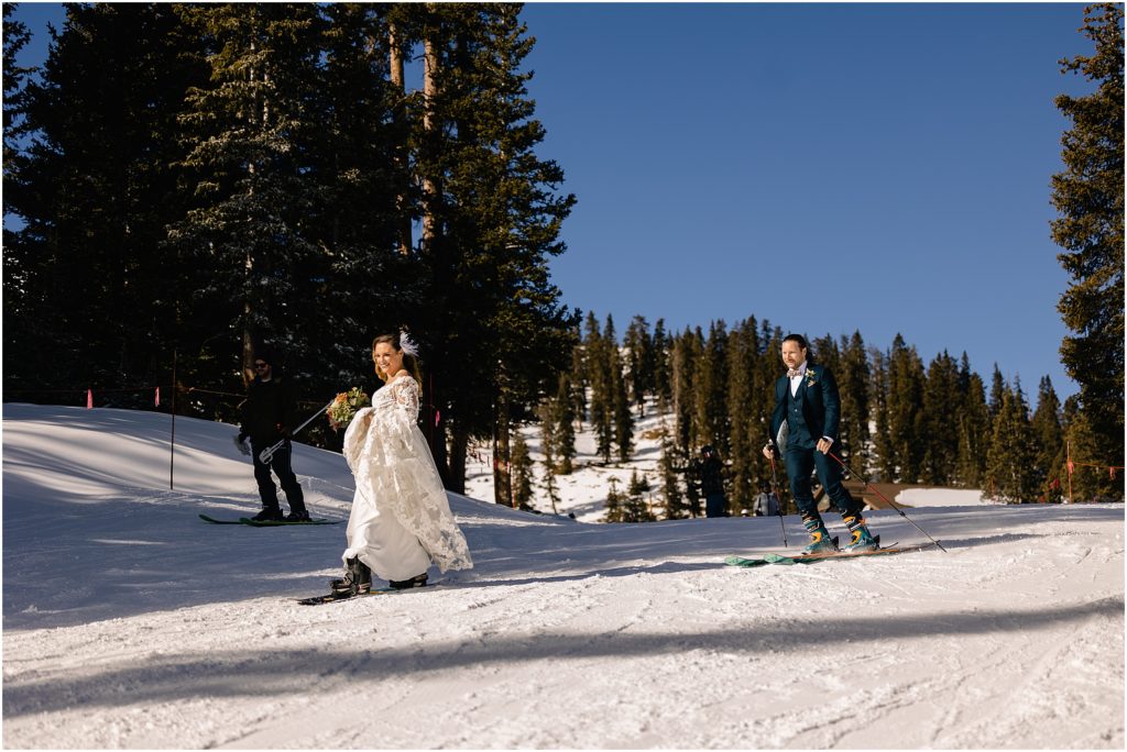 Bride and groom skiing down mountain at Arapahoe Basin after wedding ceremony