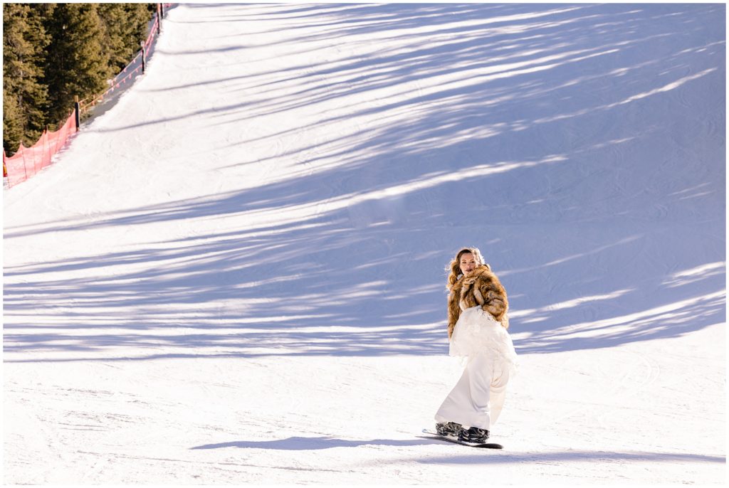 Bride snowboarding down mountain at Arapahoe Basin after wedding ceremony