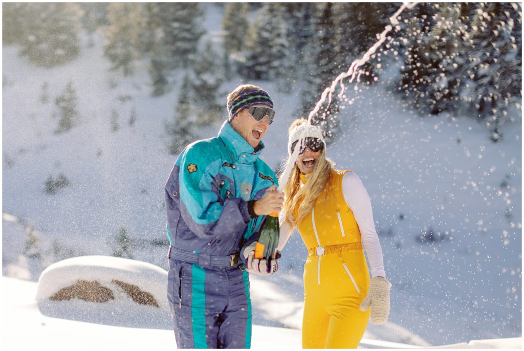 Popping champagne in winter snow for engagement session in Vail