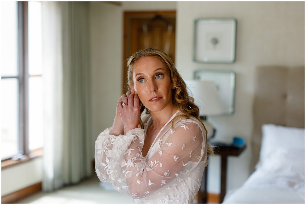 Bride putting on ear rings before wedding