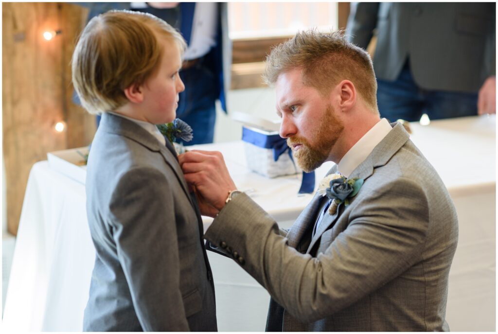 Groom helping son put on suit before wedding