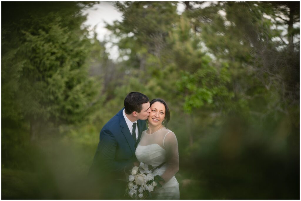 Bride and groom embracing surrounded by pine trees
