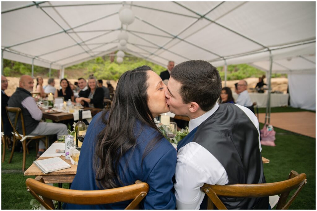 Brid and groom kissing while sitting down during reception