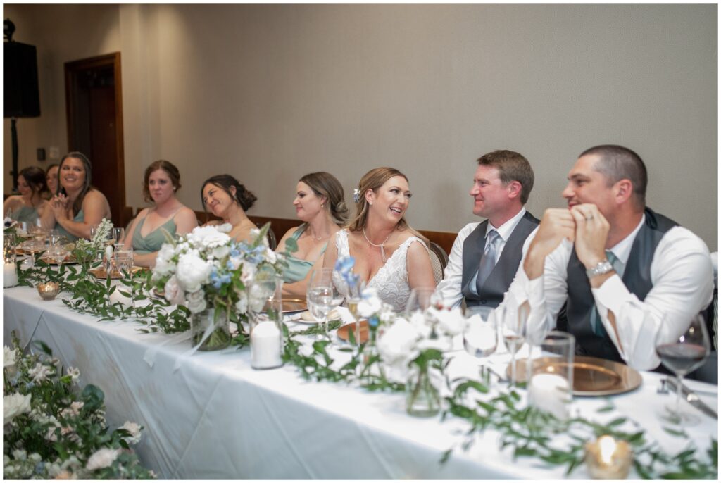 Bridal party laughing during speeches at wedding reception