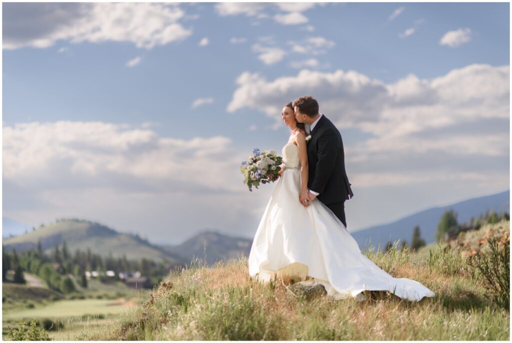 Bride and groom kissing on hill at Keystone Ranch