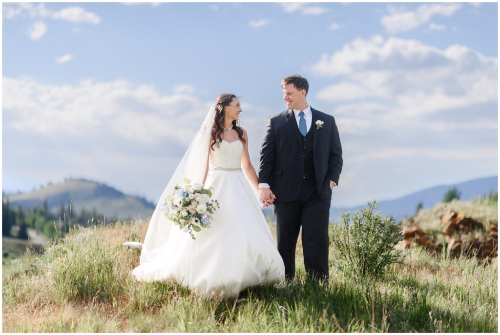 Bride and groom holding hands on hill at Keystone Ranch