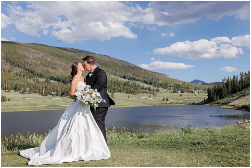 Bride and groom kissing overlooking lake at Keystone Ranch