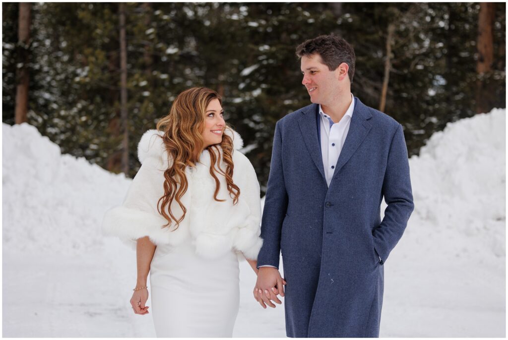 bride and groom holding hands and walking in snow