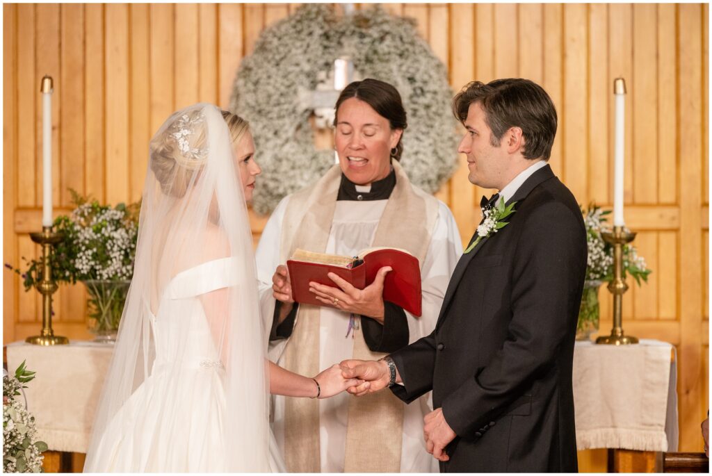 Officiant speaking to bride and groom at Church of Our Savior at Mission Farm in Vermont