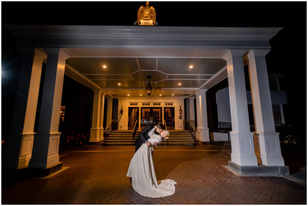 Groom dips bride during evening at Woodstock Inn entrance in Vermont