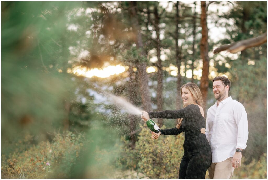 couple popping champagne during engagement session in Sapphire Point