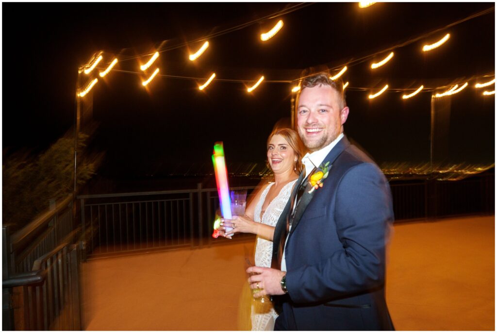 Groom and bride walking out on patio with glow sticks