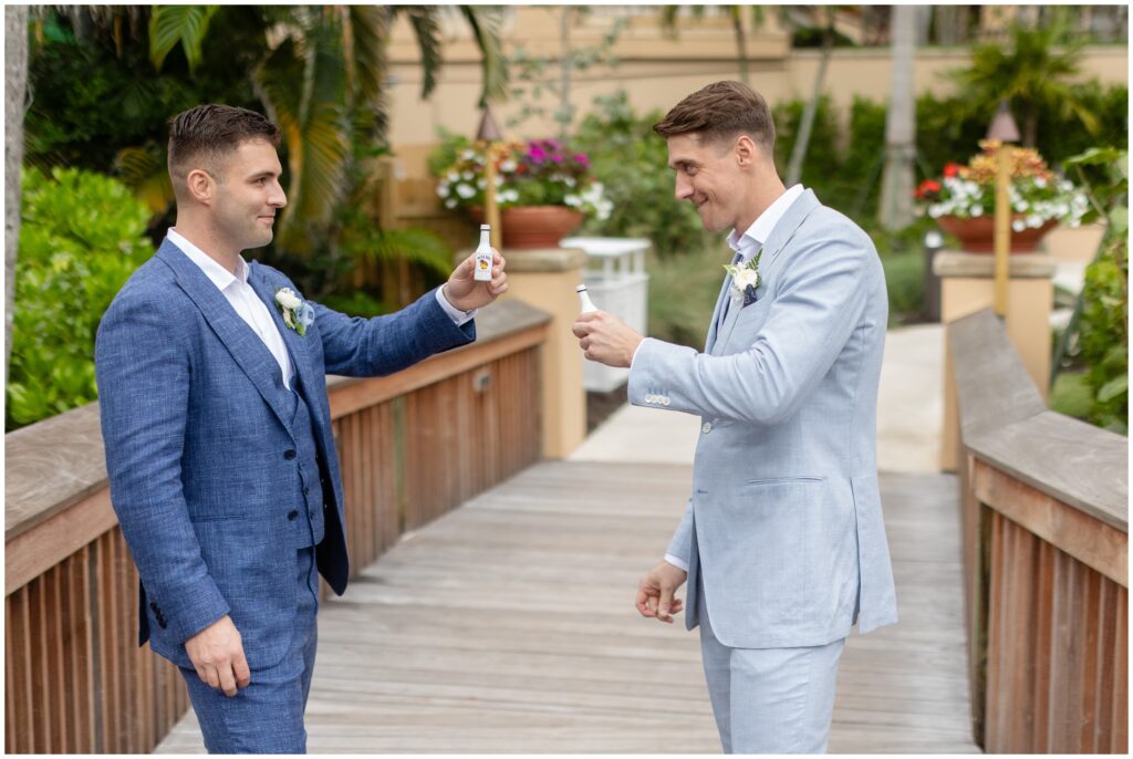 Grooms toasting outside on beach in Naples