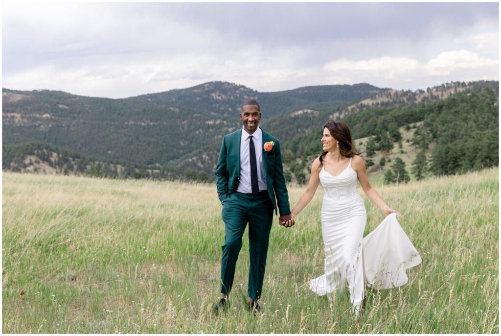 Bride and groom walking outside in grass field at Boulder Creek by Wedgewood