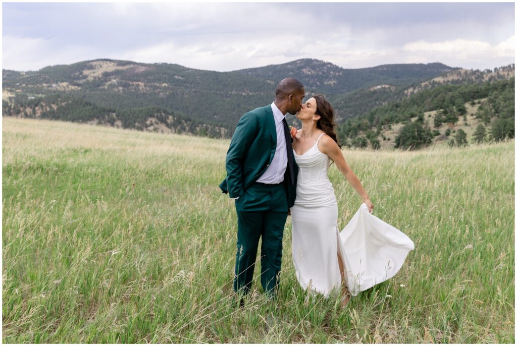 Bride and groom kiss on grass field at Boulder Creek by Wedgewood