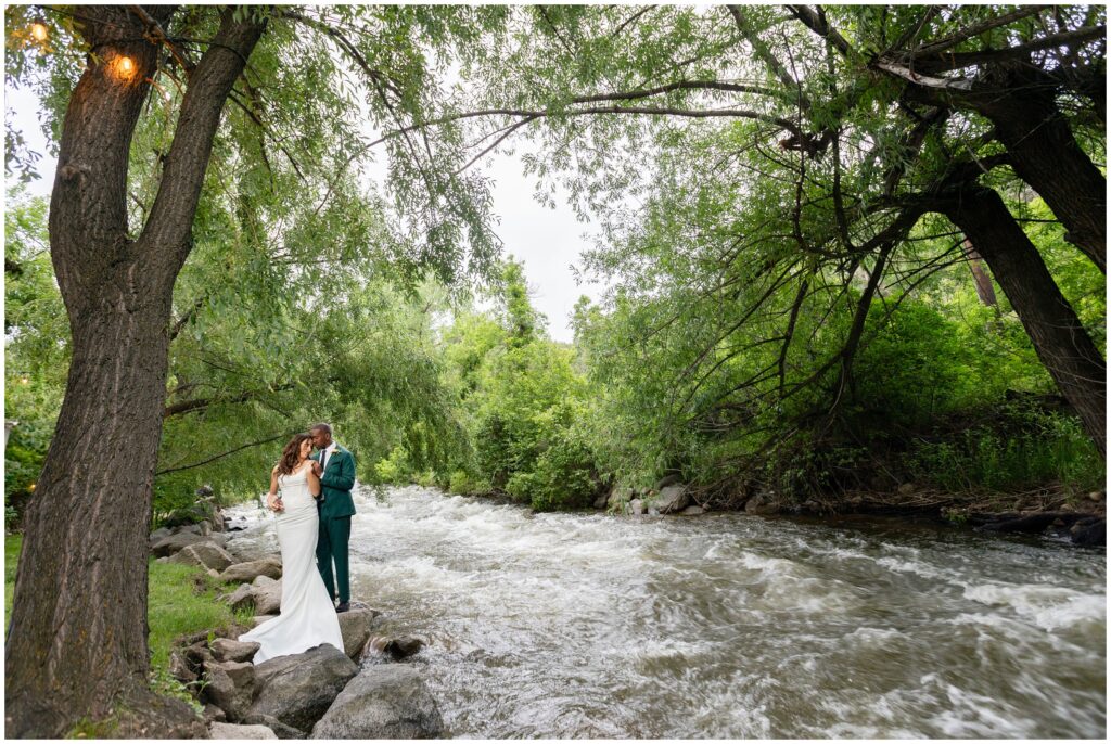 Bride and groom hugging under tree next to river at Boulder Creek by Wedgewood