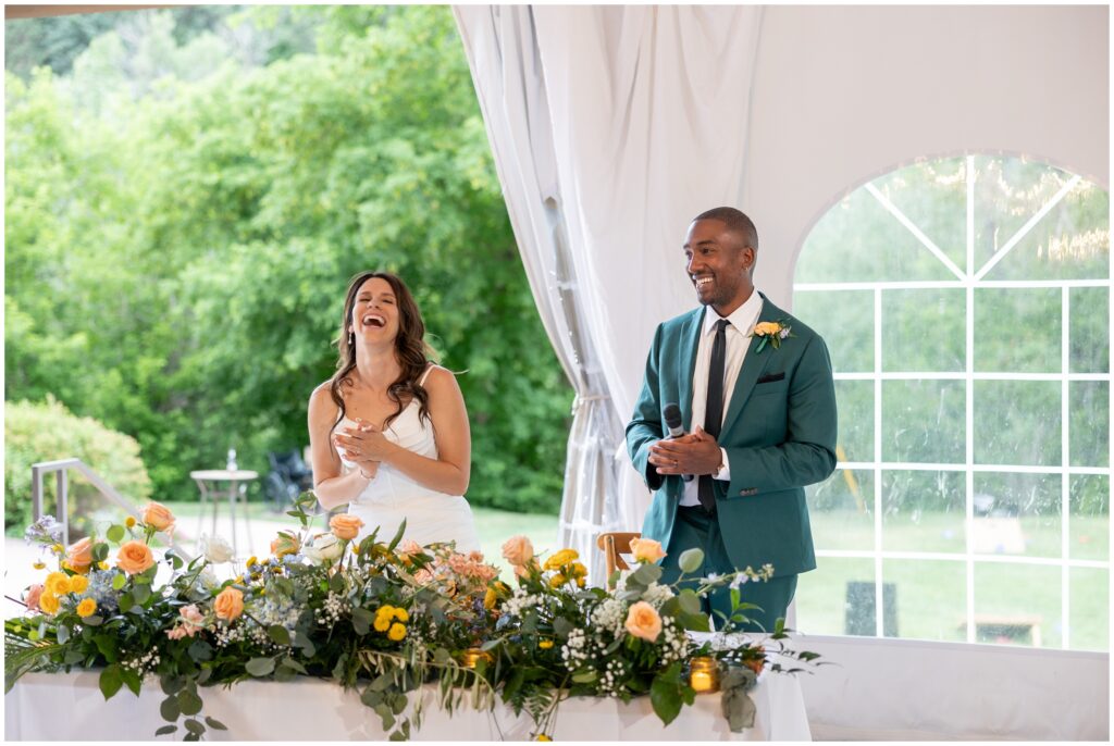 Bride and groom laughing while speaking to guests during reception