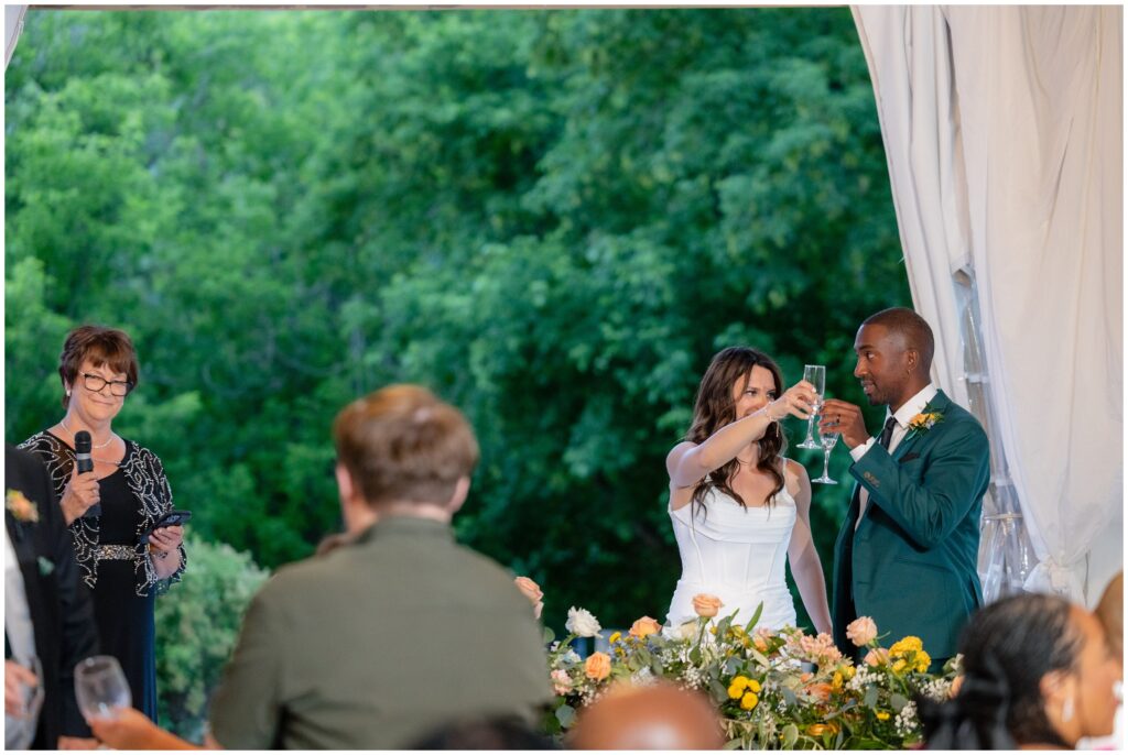 Bride and groom raising glasses at end of speech