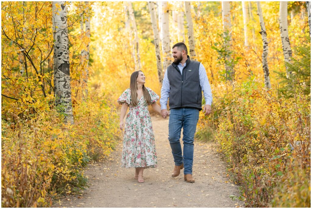 Couple walking through yellow leaves during Engagement session in Fish Creek Falls Steamboat Springs