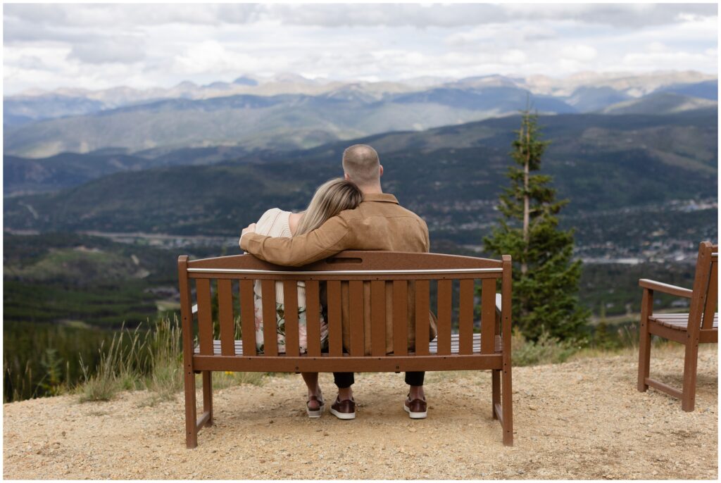 Couple sitting on bench looking out in Breckenridge after proposal