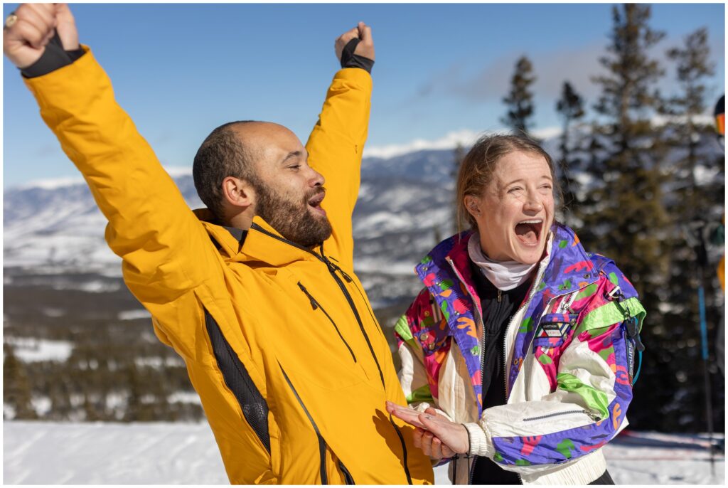 Couple celebrates during Breckenridge mountain proposal with arms up in the air