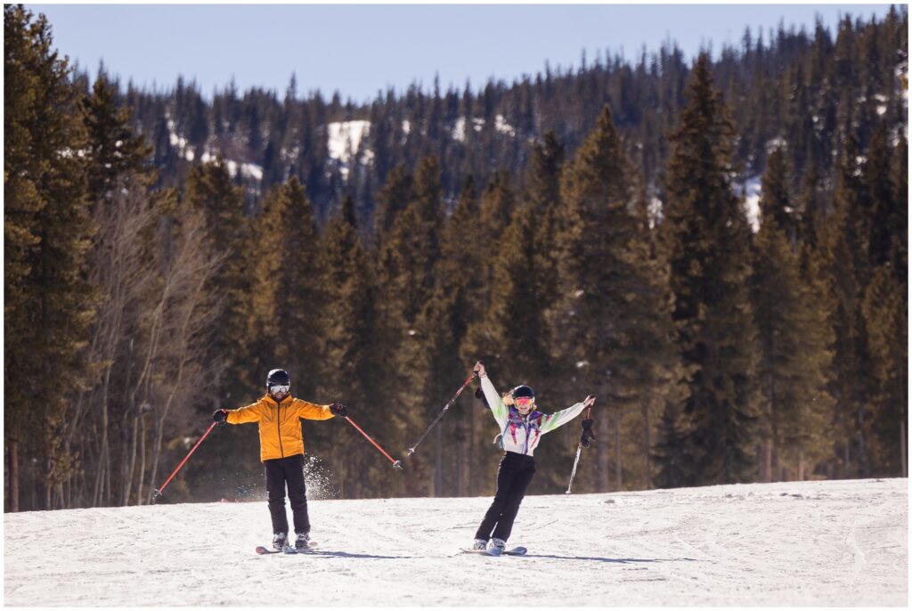 Couple holding ski poles in the air while skiing down Breckenridge mountain