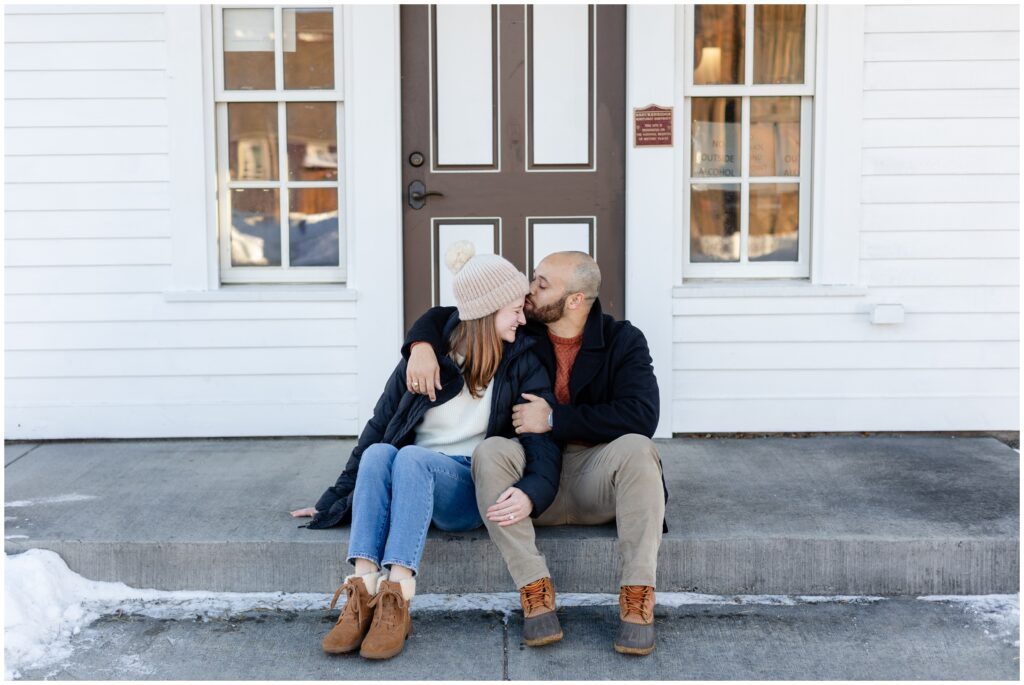 Couple hug sitting on sidewalk downtown  Breckenridge after their  proposal